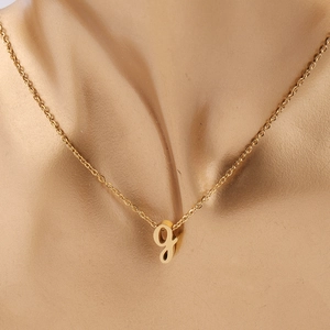 Gros plan d'un collier en acier inoxydable doré avec pendentif petite lettre g ciselée