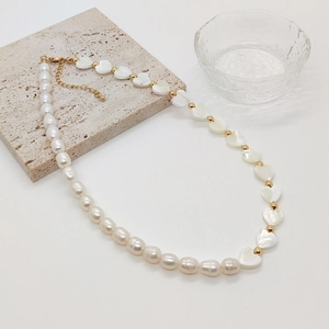 Detail of baroque pearl necklace with heart shell beads and gold clasp on stone