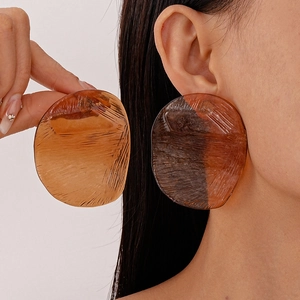 Detailed macro view of large resin earrings showing amber texture and translucent finish