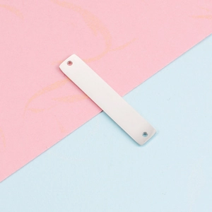 Close-up of a rectangular silver stainless steel tag with two holes on a bicolor background