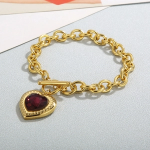 Detailed close-up of 18K gold OT buckle bracelet with heart-shaped red gemstone pendant