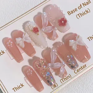 Handmade press-on nails with 3D white bows, red flowers, and pearls in nude pink