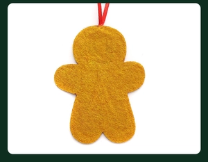 Close-up of yellow felt gingerbread man ornament with red hanging ribbon detail