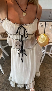 Detailed view of the layered bow straps and black piping on a white summer dress