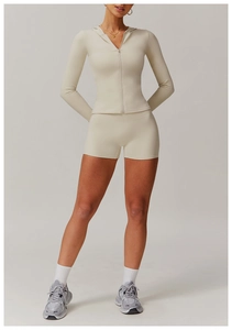 Detail of beige zip-up hooded sports top and high-waist shorts set for women's fitness