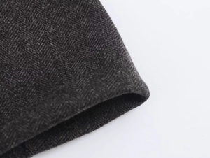 Close-up of dark grey herringbone wool fabric texture on an A-line midi skirt