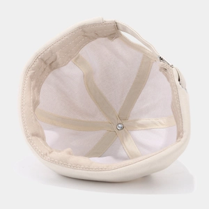 Interior detail of beige cotton docker hat showing six-panel stitch and metal rivet