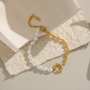 Detail of 18K gold plated stainless steel bracelet with white pearls on artistic background