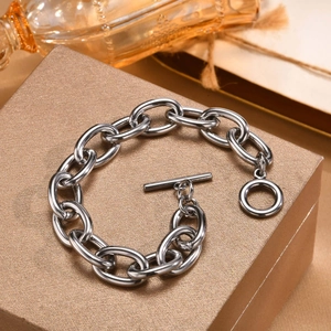 Detail of silver chunky oval link chain bracelet with OT toggle clasp on golden gift box