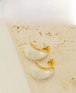 Détail de boucles d'oreilles en acier doré 18 carats avec résine blanche sur pierre