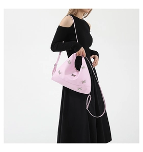 Pink nylon shoulder bag with adjustable strap and silver bow detail on black dress