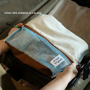 Blue travel organizer bag with mesh window and handle inside an open suitcase