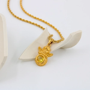 Vue macro d'un collier ange gardien doré avec pierre jaune et chaîne torsadée