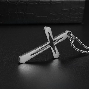 Detail shot of silver stainless steel cross pendant with star cutout on black leather