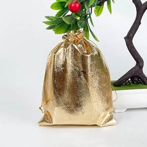 Metallic gold drawstring gift pouch for jewelry packaging on a white surface