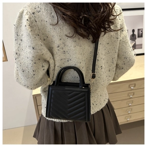 Lifestyle shot of black chevron quilted shoulder bag worn with casual autumn outfit