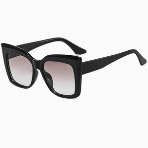 Detail of glossy black oversized cat-eye sunglasses with gradient grey lenses
