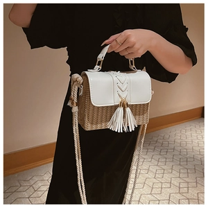 Détail du sac besace en paille avec rabat en cuir blanc et glands décoratifs