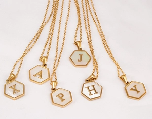 Primer plano de collares hexagonales de nácar chapados en oro 18K con varias letras