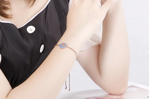 Dettaglio del bracciale regolabile in oro rosa con ciondolo in smalto blu al polso