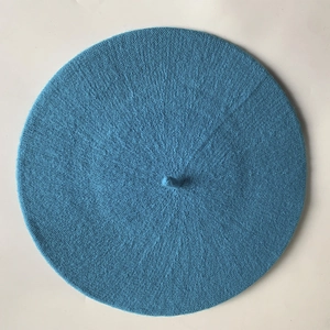 Top-down view of dark blue knit beret showing textured wool finish and stalk detail