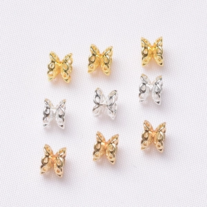 Detailed macro view of 14K gold butterfly hollow spacer beads for DIY jewelry making