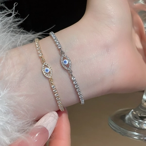 Macro detail of evil eye zircon bracelets in gold and silver finish worn on wrist