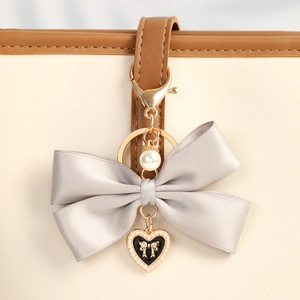 Elegant grey satin ribbon bow keychain with heart pendant and pearl on leather bag