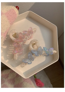 Close-up of pink and blue gradient butterfly hair claws with matte texture on a tray