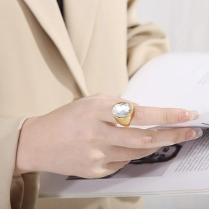 Macro detail of a large faceted crystal glass ring on a model with gold plating