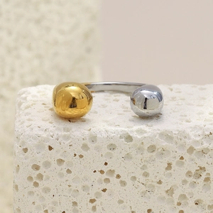 Macro shot of minimalist two-tone ball ring on white stone, showing polished metal texture
