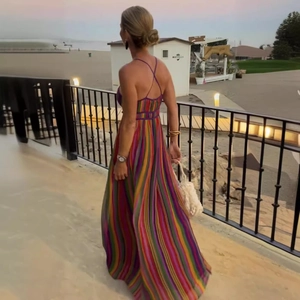 Back view of bohemian rainbow striped maxi dress with cross straps walking by seaside