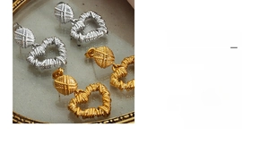 Detailed view of hollow heart pendant earrings with twisted texture in gold and silver finish