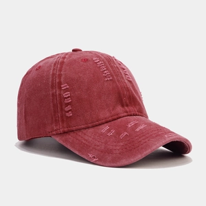 Detail view of burgundy washed cotton baseball cap with distressed ripped fabric texture