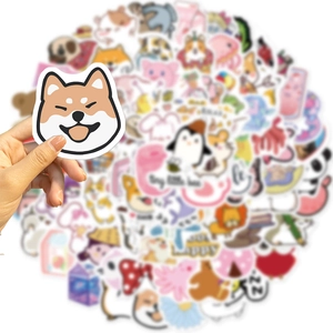 Close-up of hand holding a cute Shiba Inu cartoon sticker from a colorful 100-piece set