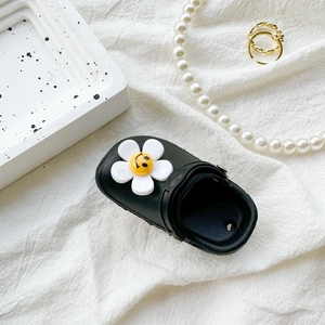 Miniature black clog-shaped coin purse with a white daisy charm on soft fabric