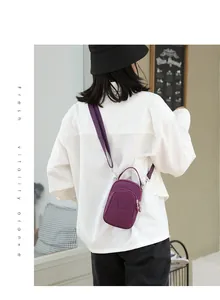 Purple nylon mini crossbody bag with three zipper layers shown on a model outdoors