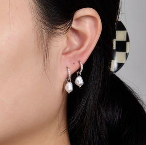 Gros plan sur des boucles d'oreilles en argent S925 avec zircons et perles baroques