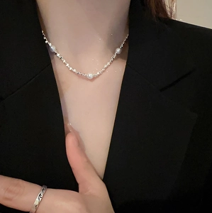 Minimalistische silberne Choker-Halskette mit Perlen und Ring auf schwarzem Blazer
