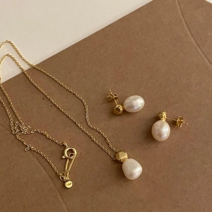 Detailed flat lay of a gold S925 silver pearl necklace and earring jewelry set