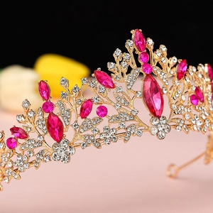Detail of golden bridal crown with magenta rhinestones and floral vine design motifs