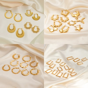 Goldene geometrische Titanstahl-Ohrringe Set mit Texturen auf beigem Seidenhintergrund