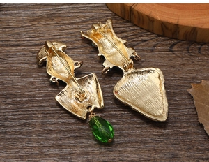 Detailed back view of gold brooch pins with green faceted teardrop charms