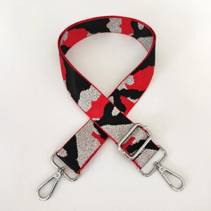 Detail of adjustable camo bag strap with silver metal buckles and woven texture