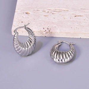 Macro detail of silver stainless steel C-shaped chunky earrings with textured screw pattern