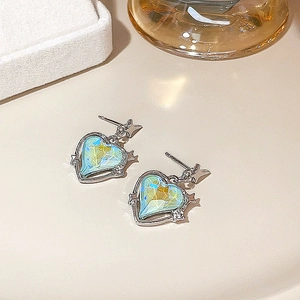 Detailed macro view of heart-shaped blue gem earrings with star design on beige background
