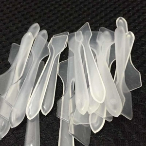 Macro shot of transparent plastic cosmetic spatulas stacked on a textured background
