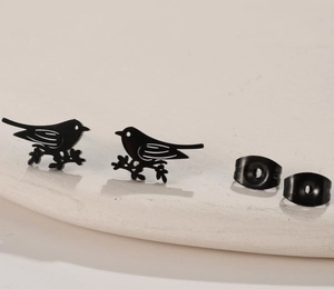 Close-up of matte black stainless steel bird studs with butterfly backings on stone