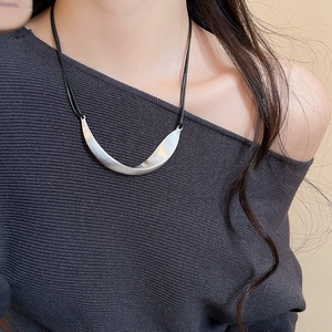 Detail of brushed silver twisted pendant necklace with a textured metallic finish