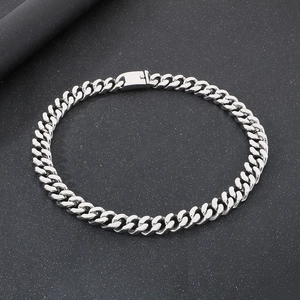 Detail shot of silver stainless steel Cuban chain necklace with secure clasp on black background